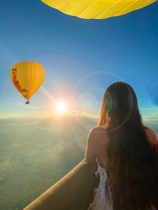 Dreamily looking at a hot air balloon from another basket