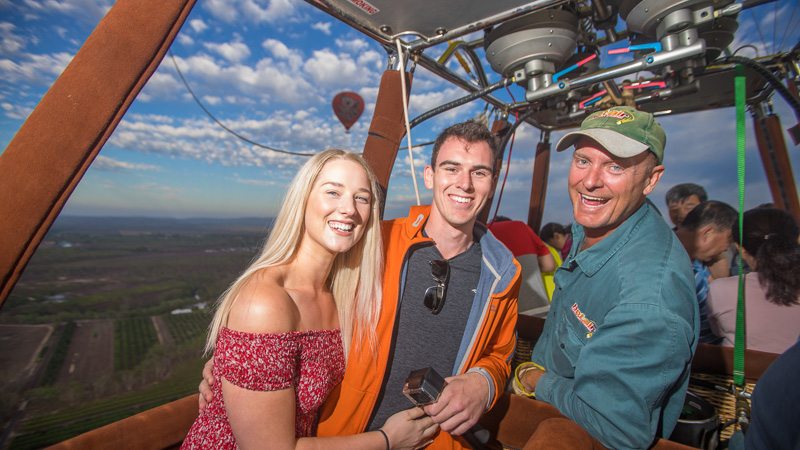 Smiling couple with hot air balloon pilot