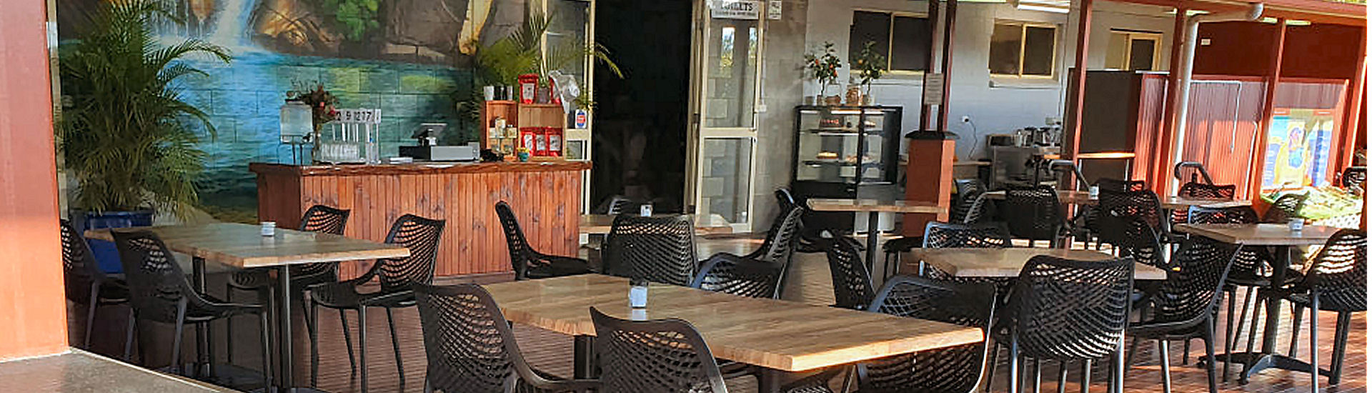 Inside Savannah Café at the Mareeba Heritage Centre, tables and chairs in front of the Emerald Falls mural