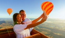 A couple taking a selfie from a hot air balloon basket while in flight